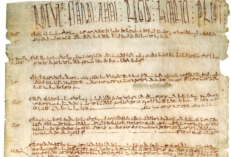 Aged parchment paper with a large written heading and several blocks of written text.